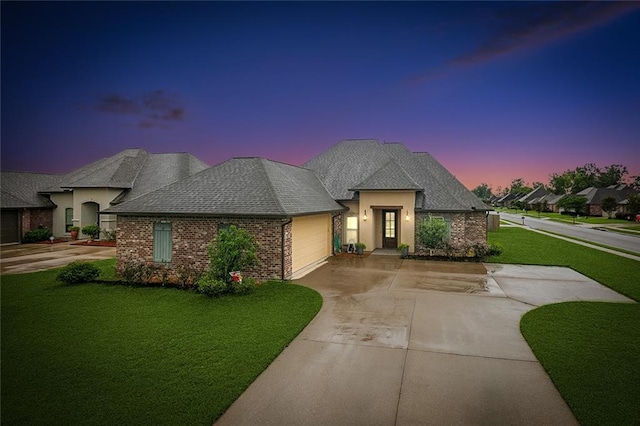 french country style house featuring a garage and a lawn