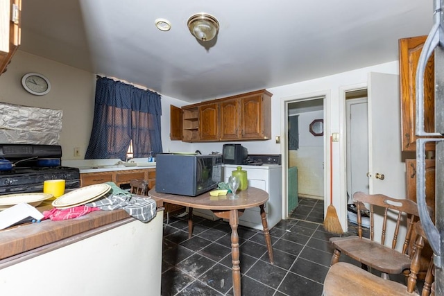 kitchen featuring dark tile patterned floors, black appliances, and separate washer and dryer