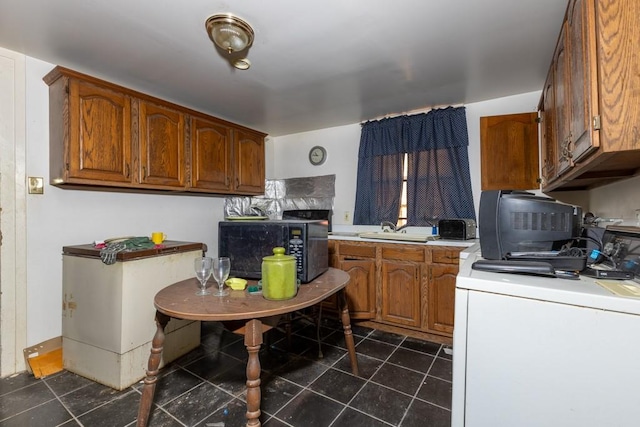 kitchen featuring dark tile patterned flooring, sink, and washer / clothes dryer