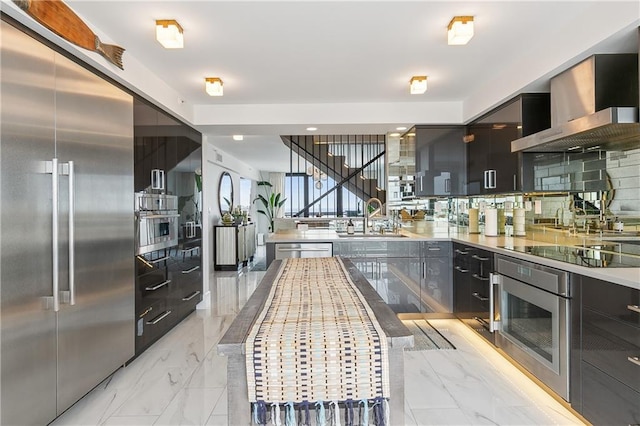 kitchen with appliances with stainless steel finishes, wall chimney range hood, tasteful backsplash, and sink