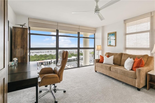 carpeted home office with ceiling fan and a water view