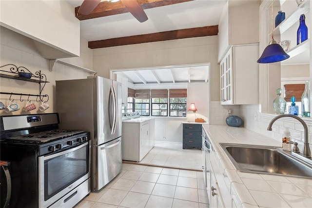 kitchen featuring washer / dryer, beamed ceiling, sink, white cabinetry, and appliances with stainless steel finishes