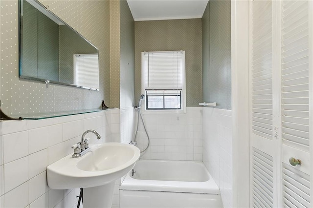 bathroom featuring tile walls, sink, and a bathing tub