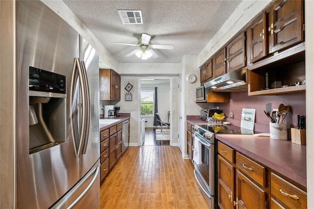 kitchen with ceiling fan, a textured ceiling, stainless steel appliances, and light hardwood / wood-style flooring