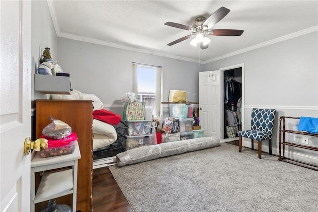 bedroom with ceiling fan, crown molding, dark wood-type flooring, and a walk in closet