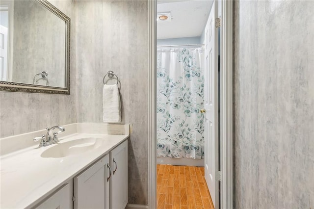 bathroom with wood-type flooring, walk in shower, and vanity