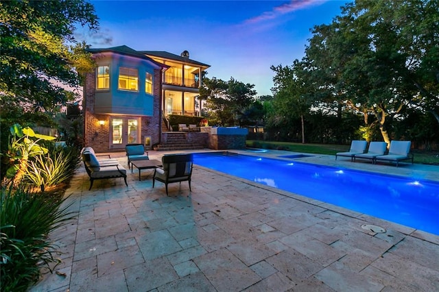 pool at dusk featuring a patio and an outdoor living space