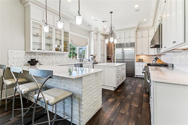 kitchen with pendant lighting, a center island, high end appliances, a kitchen breakfast bar, and dark hardwood / wood-style flooring