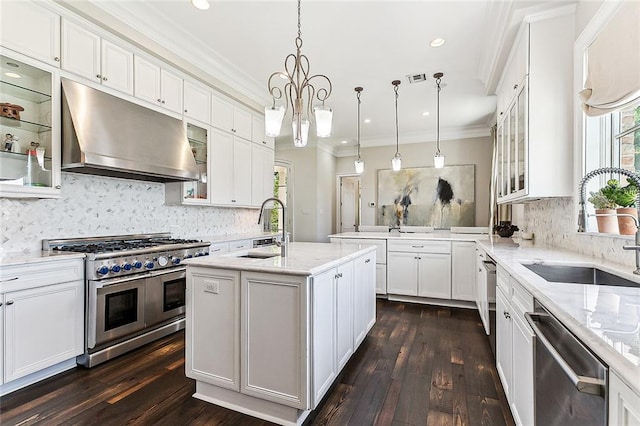 kitchen with white cabinets, hanging light fixtures, a kitchen island with sink, appliances with stainless steel finishes, and dark hardwood / wood-style flooring