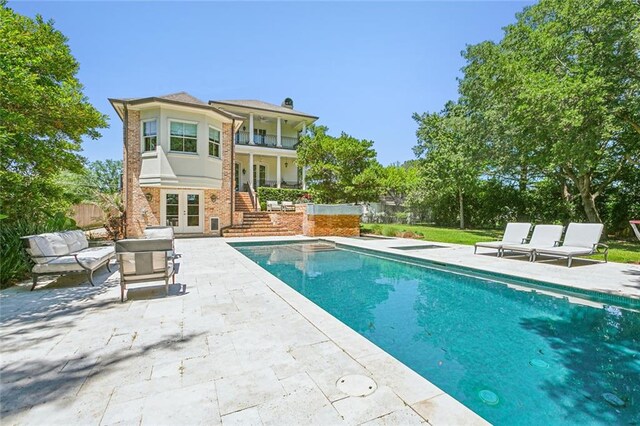 rear view of house with a balcony, an outdoor living space, and a patio