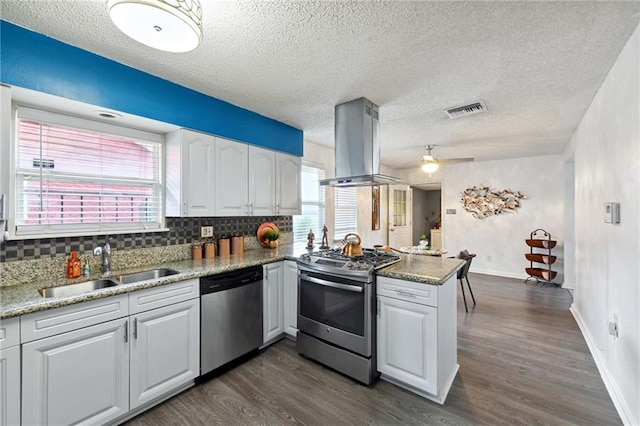 kitchen featuring kitchen peninsula, island exhaust hood, white cabinetry, stainless steel appliances, and dark hardwood / wood-style flooring