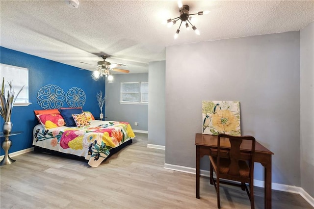 bedroom featuring ceiling fan, a textured ceiling, and light wood-type flooring