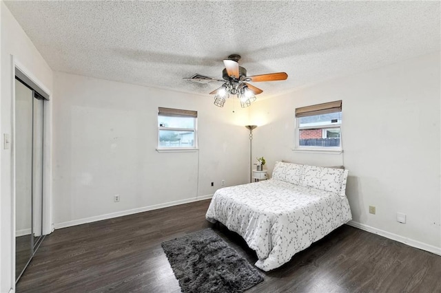 bedroom with a textured ceiling, dark hardwood / wood-style floors, ceiling fan, and a closet