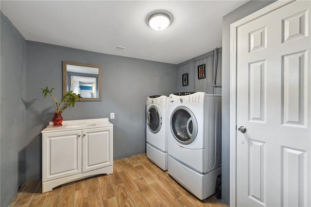 laundry area with washer and clothes dryer, cabinets, and light hardwood / wood-style floors