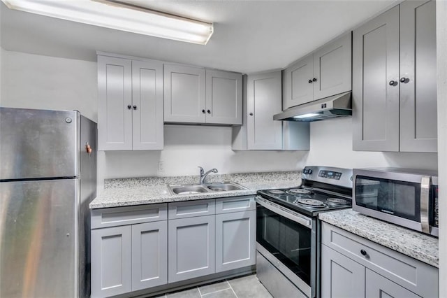 kitchen featuring stainless steel appliances, light stone countertops, sink, and light tile patterned floors