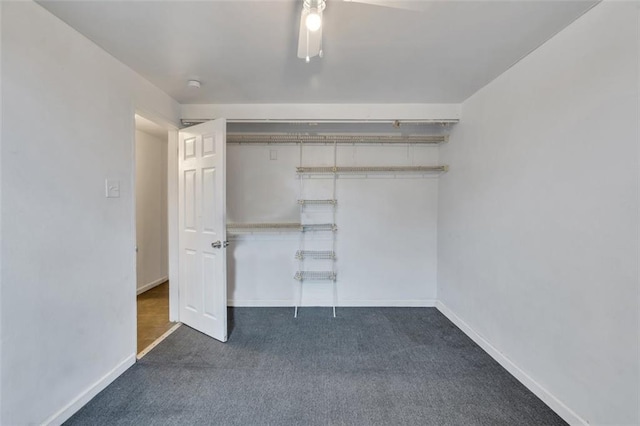 unfurnished bedroom featuring ceiling fan, a closet, and dark colored carpet