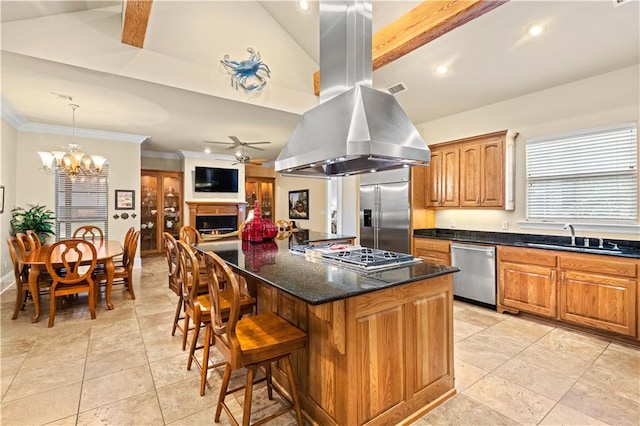 kitchen featuring hanging light fixtures, island exhaust hood, appliances with stainless steel finishes, a breakfast bar area, and ceiling fan with notable chandelier