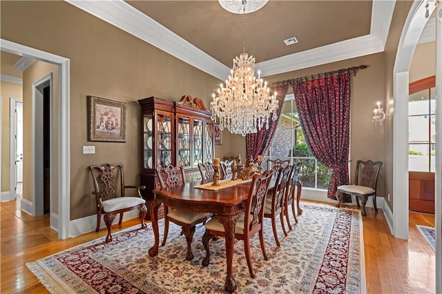 dining space with light hardwood / wood-style flooring, a chandelier, and ornamental molding