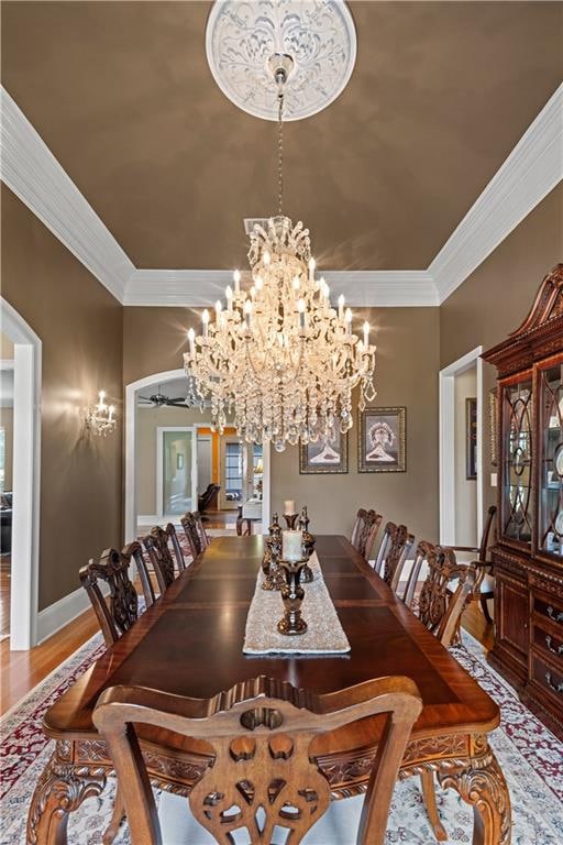 dining area featuring ornamental molding, ceiling fan with notable chandelier, and hardwood / wood-style flooring