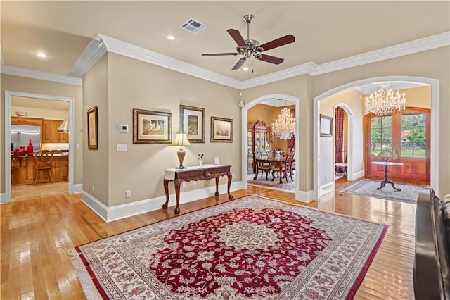 interior space featuring crown molding, ceiling fan with notable chandelier, and hardwood / wood-style floors