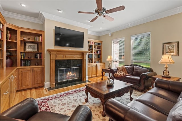 living room featuring light wood-type flooring, crown molding, ceiling fan, and a high end fireplace