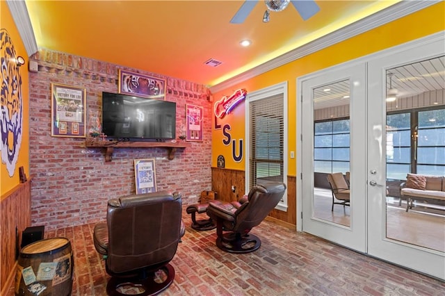 interior space featuring crown molding, ceiling fan, french doors, and brick wall