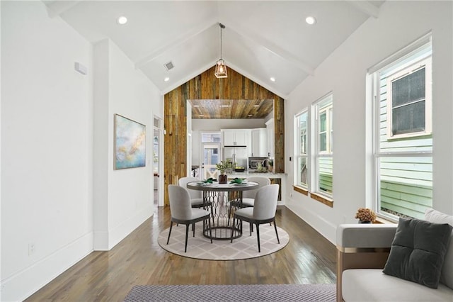 dining area with high vaulted ceiling, beam ceiling, and hardwood / wood-style flooring