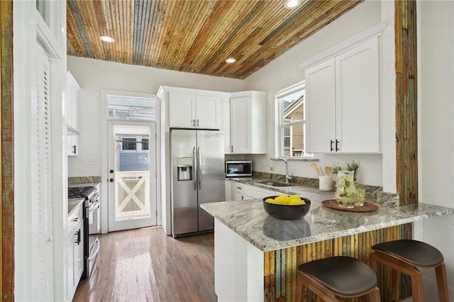 kitchen with appliances with stainless steel finishes, white cabinetry, dark wood-type flooring, wooden ceiling, and sink