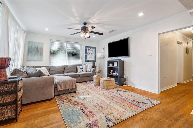 living room with ornamental molding, light wood-type flooring, and ceiling fan