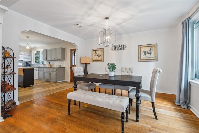 dining space featuring a notable chandelier, a healthy amount of sunlight, and light wood-type flooring