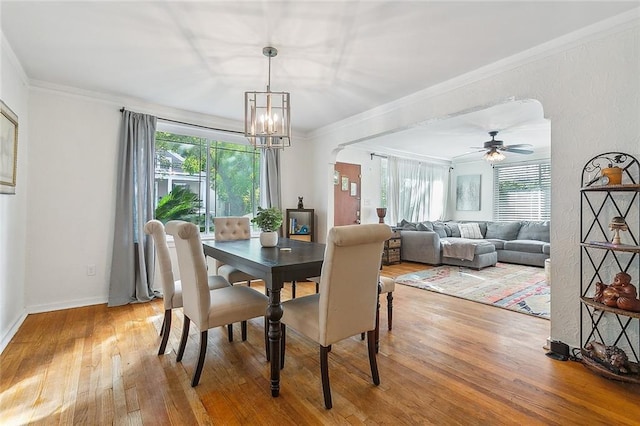 dining space with crown molding, wood-type flooring, and ceiling fan with notable chandelier