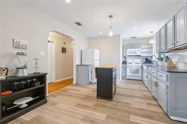 kitchen with white appliances, pendant lighting, light hardwood / wood-style floors, sink, and butcher block countertops