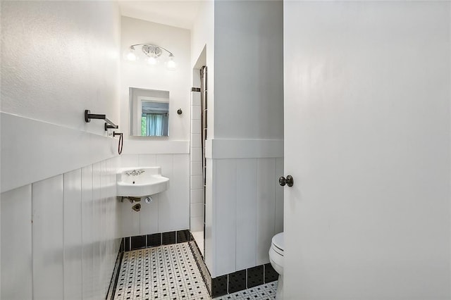 bathroom featuring toilet, a shower, and tile walls