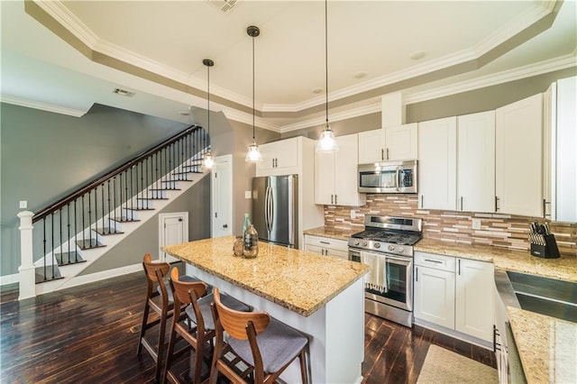 kitchen with pendant lighting, white cabinets, appliances with stainless steel finishes, and dark hardwood / wood-style flooring