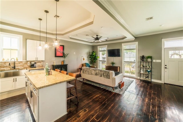 kitchen featuring dark wood-type flooring, white cabinets, a kitchen island, pendant lighting, and sink