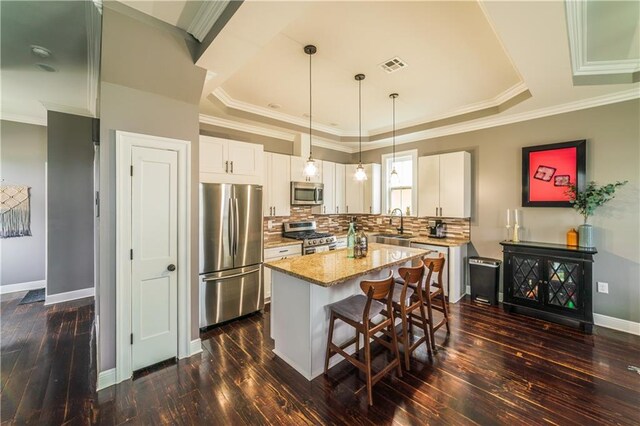 kitchen with white cabinets, decorative light fixtures, stainless steel appliances, dark hardwood / wood-style floors, and a center island