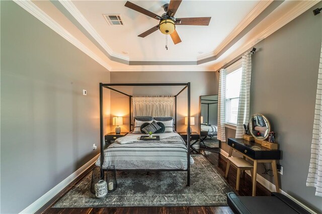 bedroom featuring ceiling fan, a tray ceiling, ornamental molding, and wood-type flooring