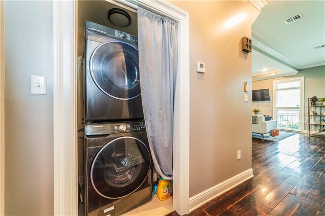 clothes washing area with crown molding, dark wood-type flooring, and stacked washer and clothes dryer