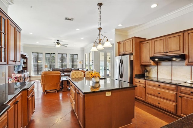 kitchen with hanging light fixtures, stainless steel fridge, black electric cooktop, a center island, and decorative backsplash