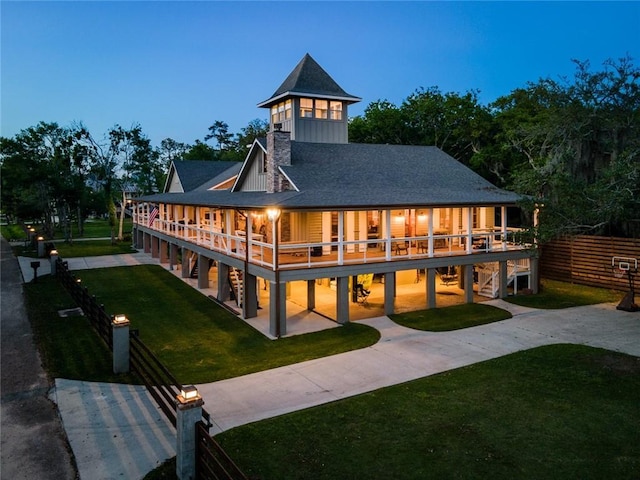 back of house featuring board and batten siding, concrete driveway, a yard, and a patio