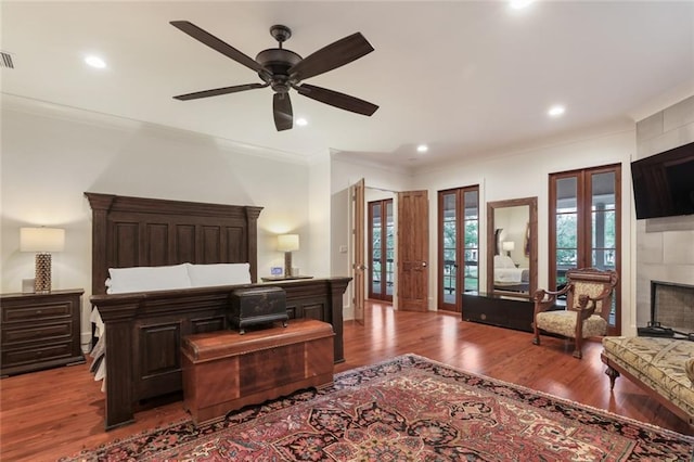 115 Holly St, Mandeville, LA 70448 - bedroom featuring wood finished floors, crown molding, french doors, recessed lighting, and a tiled fireplace