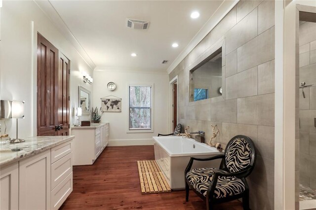 115 Holly St, Mandeville, LA 70448 - full bathroom featuring ornamental molding, wood finished floors, a freestanding bath, two vanities, and tiled shower