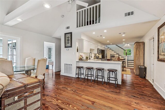 115 Holly St, Mandeville, LA 70448 - living room with dark wood finished floors, stairs, baseboards, recessed lighting, and high vaulted ceiling