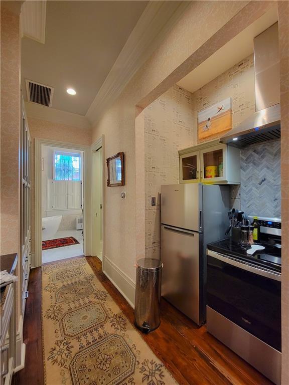 kitchen with backsplash, wall chimney exhaust hood, stainless steel appliances, and dark wood-type flooring