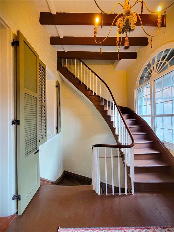 stairs featuring beamed ceiling and hardwood / wood-style flooring