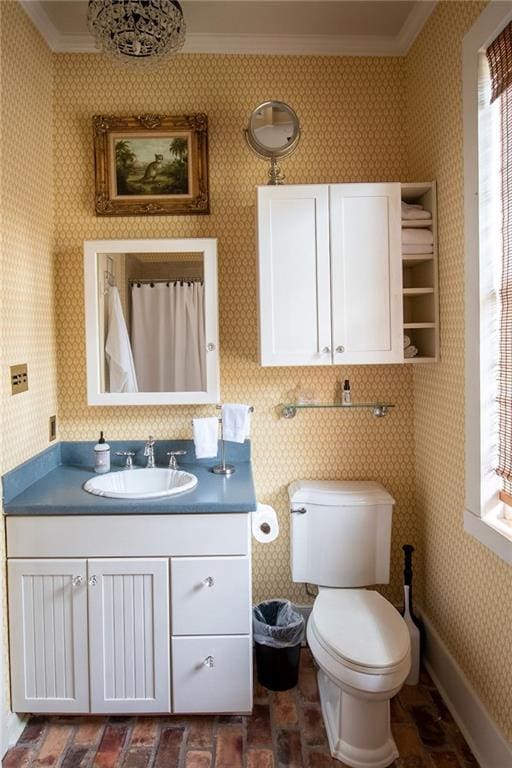 bathroom featuring toilet, vanity, and ornamental molding