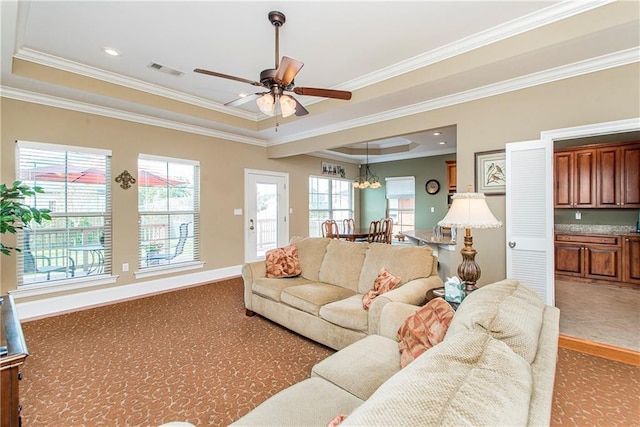 living room with ceiling fan with notable chandelier, a raised ceiling, and ornamental molding