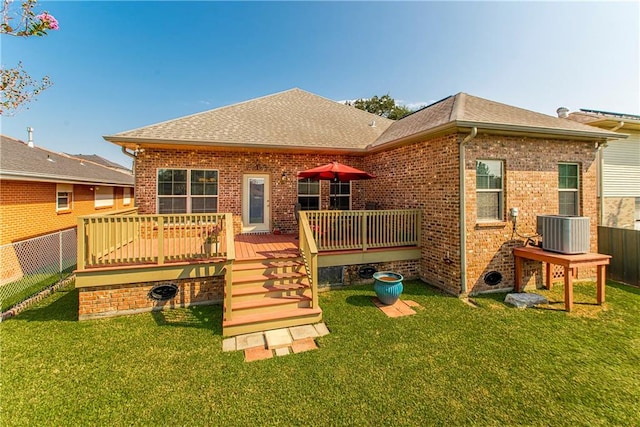 rear view of property with a lawn, a wooden deck, and central AC