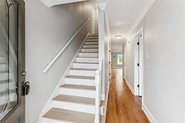 stairway with hardwood / wood-style floors and ornamental molding