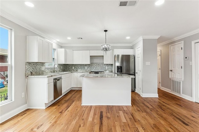 kitchen with a center island, appliances with stainless steel finishes, a healthy amount of sunlight, and light wood-type flooring